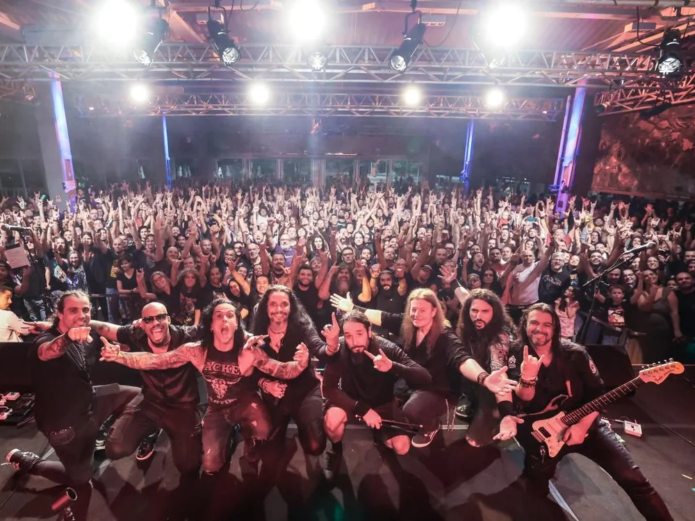 Roland Grapow, Fabio Carito and the band kneeling on stage in front of a packed crowd