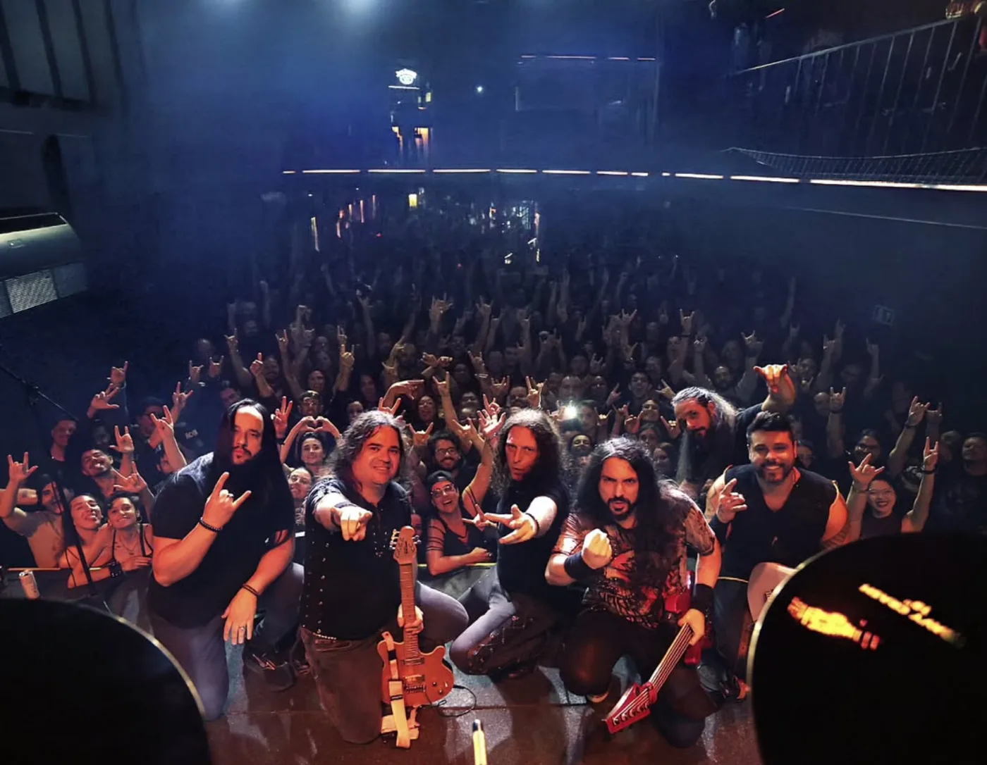 Fabio Lione, Fabio Carito and the band kneeling on stage in front of the crowd at the end of the show