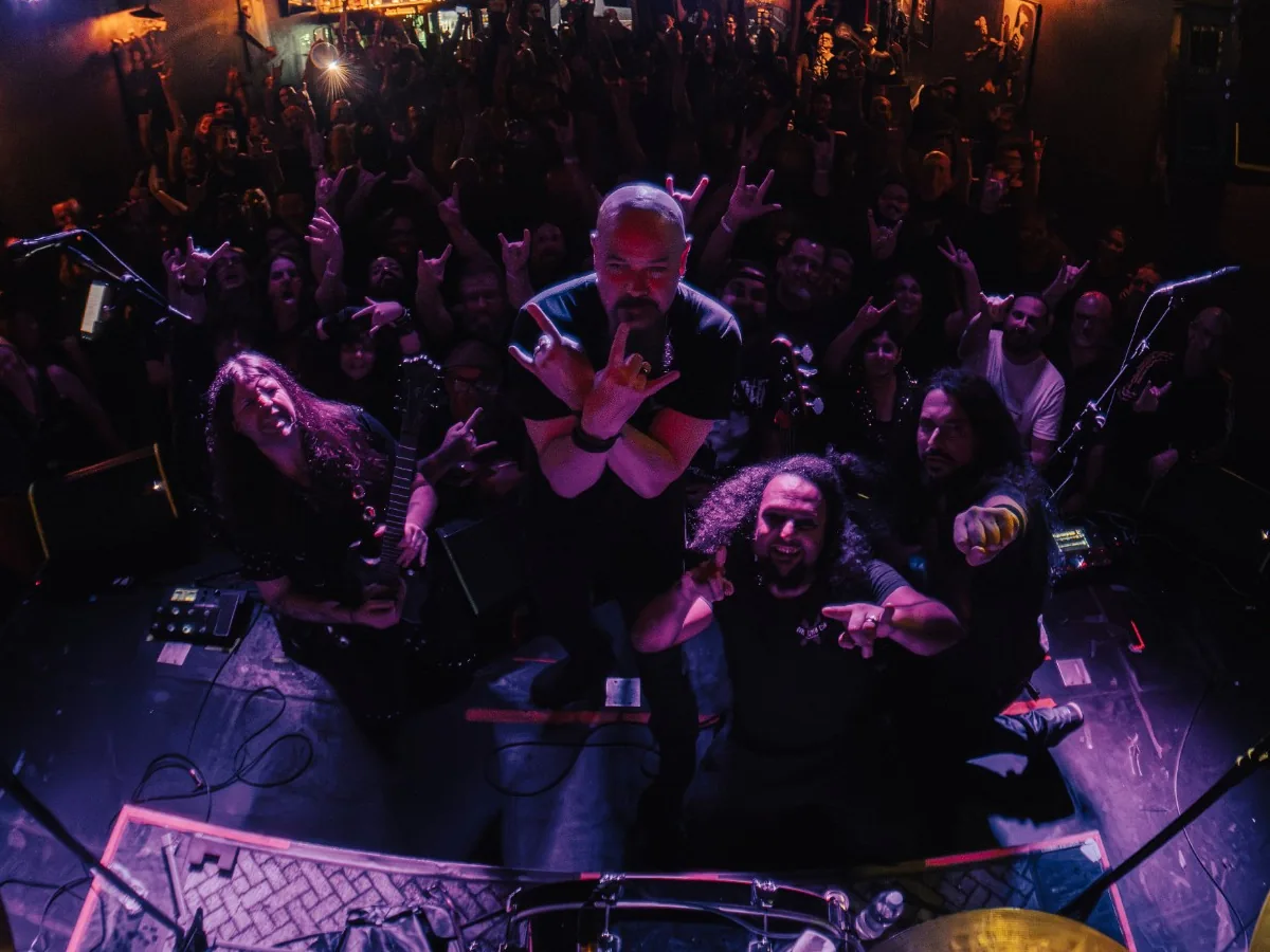Robert Lowe crossing his arms with the horns, Fabio Carito and the band around him, seen from the drum riser